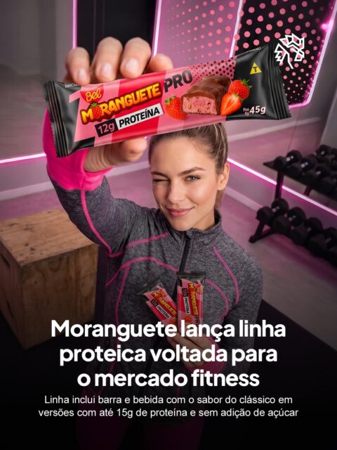 O mercado de snacks proteicos cresce rápido no Brasil e pressiona marcas tradicionais a encontrar seu espaço nesse território. O Moranguete, um dos chocolates mais afetivos da memória do consumidor brasileiro, decide entrar nessa disputa com um sentimento que poucas marcas hoje em dia têm: nostalgia.
O Moranguete Pro chega em duas frentes: uma barra de 45g com 12g de proteína e cobertura sem adição de açúcar, e um shake de 250ml com 15g de proteína e zero lactose. Os dois produtos mantêm o sabor característico do clássico adaptado ao contexto fitness.
A jogada posiciona o produto em um segmento em expansão sem abrir mão da memória afetiva construída em décadas, usando o reconhecimento do clássico como atalho para conquistar um novo público.