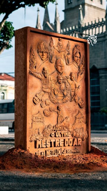 Há tempos os fãs enxergam em Feira de Santana uma versão real de Ba Sing Se, a colossal capital do Reino da Terra. A comparação corre solta nas redes e já virou meme recorrente entre os baianos. A Netflix percebeu o movimento e decidiu entrar na conversa.

Para transformar a piada em homenagem, a plataforma convidou @zaiaescultor, que ergueu uma obra em areia barrada com o elenco da trama em alto-relevo. A peça ficou em exposição gratuita neste domingo, no Paço Municipal, no centro da cidade. Usar o próprio barro como matéria-prima ainda dialoga com a dobra do elemento que move o enredo.

No fim, quem ganha é a cidade, que viu uma brincadeira da internet virar arte na praça e ainda colocou o trabalho de um artista local no mapa ao lado de um dos maiores lançamentos do momento.